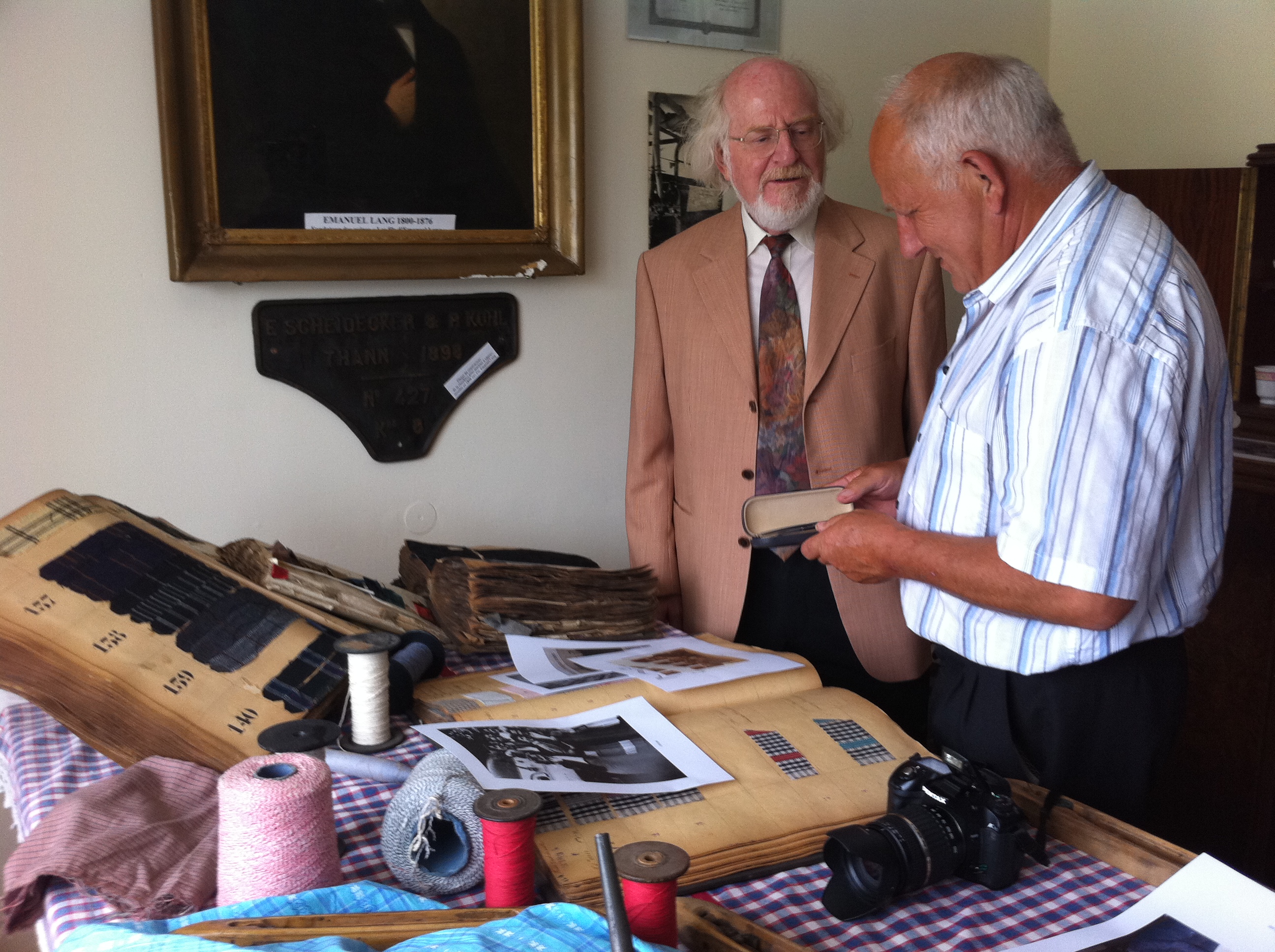 Joseph Haas montre à Antoine Lang des échantillons de tissus fabriqués par l'usine Lang