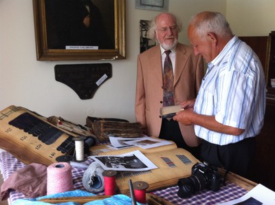 Joseph Haas montre à Antoine Lang des échantillons de tissus fabriqués par l'usine Lang