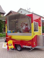 Vue du camion E Viva La Paella sur la place de la Mairie. Le vendeur entrain de garnir une barquette de paëlla.