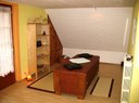 La salle de massage avec la table de massage en bois massif au centre de la pièce dans les locaux du Centre de l'Harmonie à Steinsoultz.