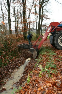 Le ratissage avec fourche et tracteur de feuilles mortes sur un sentier forestier de Waldighoffen